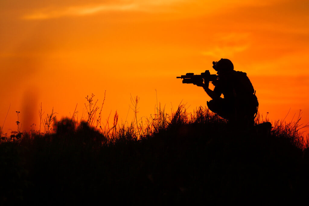 Silhouette of military soldier or officer with weapons at sunset